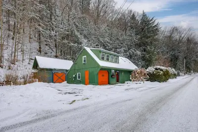 a green and orange barn on a snow covered road at Hike, Fish, Hunt! Green Mountain Home By River