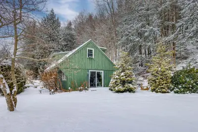 a green barn with christmas trees in the snow at Hike, Fish, Hunt! Green Mountain Home By River