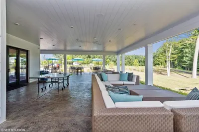 a living room with couches and a table with umbrellas at Landing Apartments - The Preserve at Great Pond in Windsor