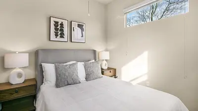 a bedroom with a bed with two lamps and a window at Landing Apartments - The Preserve at Great Pond in Windsor