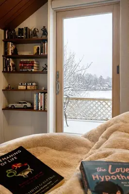a book sitting on a couch in front of a window at Cherry Blossom Lake House in Lake Peekskill