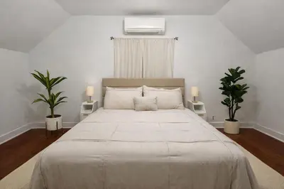 a bedroom with a large white bed with two plants at Cherry Blossom Lake House in Lake Peekskill