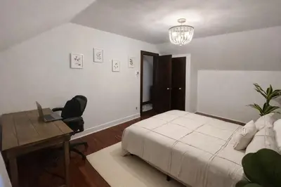 a bedroom with a bed and a desk with a laptop at Cherry Blossom Lake House in Lake Peekskill