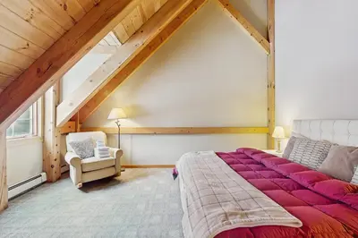 a attic bedroom with a large bed and a chair at Grouse Lane 12C in Dover