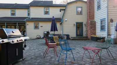 a patio with chairs and an umbrella and a grill at Long Island Nature Retreat with Peloton with Shared Pool in Glen Head