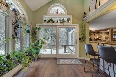 a living room with a large window and plants at 3 Mi to Mount Snow Spacious West Dover Home in West Dover
