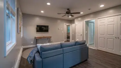 a blue couch in a living room with a ceiling fan at Luxe Lakefront Paradise! King Beds, Private Dock, Gourmet Kitchen, Theatre and Game Room!