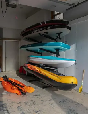 a group of surfboards and kayaks on display in a room at Luxe Lakefront Paradise! King Beds, Private Dock, Gourmet Kitchen, Theatre and Game Room!
