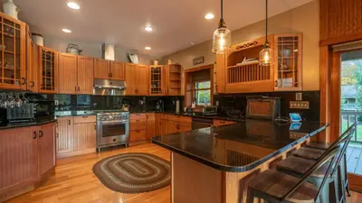 a kitchen with wooden cabinets and a black counter top at Luxe Lakefront Paradise! King Beds, Private Dock, Gourmet Kitchen, Theatre and Game Room!