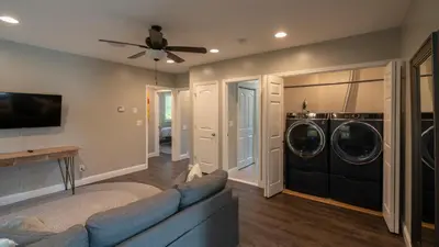 a living room with a couch and a washer and dryer at Luxe Lakefront Paradise! King Beds, Private Dock, Gourmet Kitchen, Theatre and Game Room!