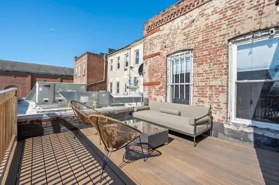 a patio with a couch and chairs on a balcony at Luxury and Modern Apt with Patio only 10 Min to Times Square in Jersey City
