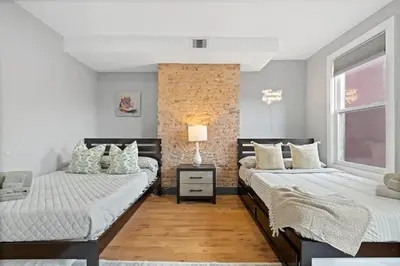 a bedroom with two beds and a brick wall at Luxury and Chic 2BR 2BA Apt only 15 Mins to NYC & Hoboken in Jersey City