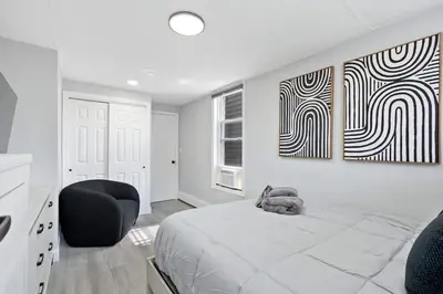 a bedroom with a bed and a black chair at New and Beautiful 2BR Apt in Prime Spot 20 Min to NYC in Jersey City