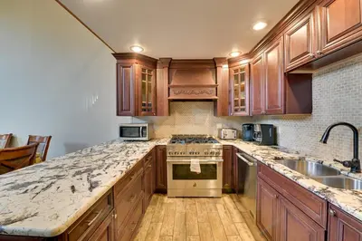 a kitchen with wooden cabinets and granite counter tops at Walk to Hunter Village! Family Ski Retreat with Deck in Lanesville