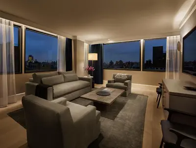 a living room with a couch and chairs and windows at 11 Howard, New York, a Member of Design Hotels in New York