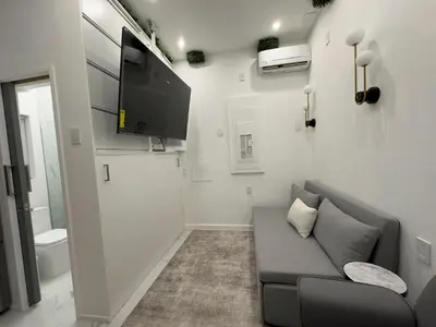 a living room with a couch and a flat screen tv at Modern Tiny Home Fast NYC Access Private in Jersey City