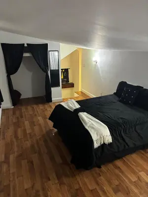 a bedroom with a black bed and a wooden floor at a whole house in Schenectady