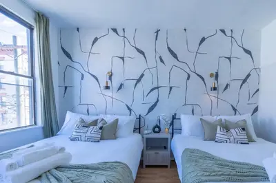 two beds in a bedroom with a mural of trees at New Calm Cocoon by Train We Pay Half Parking, Sleeps 6 in Hoboken