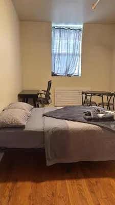 a bed in a room with two tables and a window at New York City Guesthouse 3 in New York
