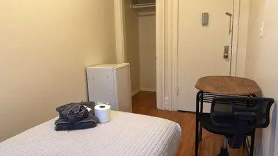 a bedroom with a bed and a chair with a bag on it at New York City Guesthouse 3 in New York
