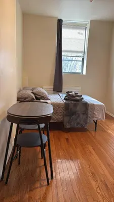 a bedroom with a bed and a table with a chair at New York City Guesthouse 3 in New York