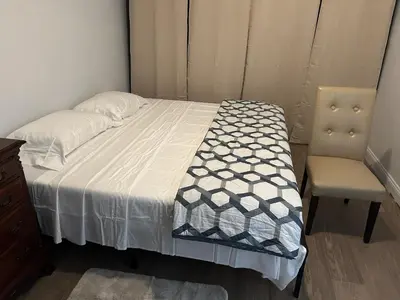 a bed and a chair in a small room at 1BR Apartment - Unit A - With Parking and 10min Walk to NYC Train Station in Mount Vernon