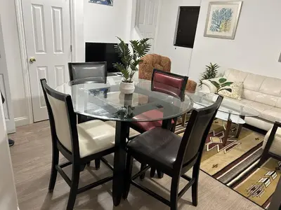 a dining room with a glass table and chairs at 1BR Apartment - Unit A - With Parking and 10min Walk to NYC Train Station in Mount Vernon