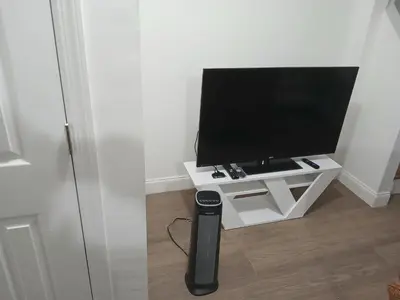 a tv sitting on a white stand in a room at 1BR Apartment - Unit A - With Parking and 10min Walk to NYC Train Station in Mount Vernon