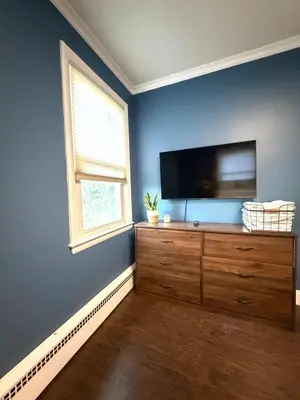 a living room with a flat screen tv on a blue wall at Entire house for big group-minutes from Hartford in East Hartford