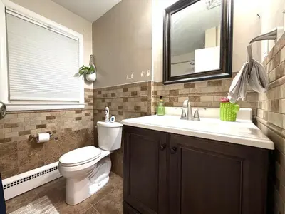 a bathroom with a toilet and a sink and a mirror at Entire house for big group-minutes from Hartford in East Hartford