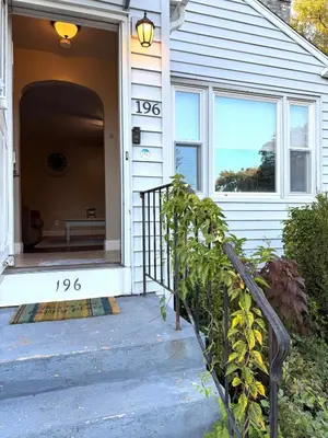 a porch of a white house with a sign on it at Entire house for big group-minutes from Hartford in East Hartford