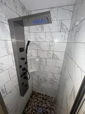 a bathroom with a shower with white tiles at Comfortstayrus in Orange