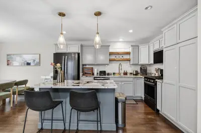 a kitchen with white cabinets and a large island with bar stools at The Willowbrook Catskills in Athens