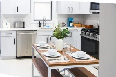 a kitchen with white cabinets and a wooden table at Stylish Two Bedroom Apartment with Free Indoor Parking in West New York