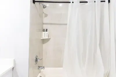 a bathroom with a shower with a white shower curtain at Stylish Two Bedroom Apartment with Free Indoor Parking in West New York