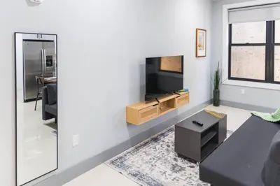 a living room with a couch and a flat screen tv at 20 Minutes to Times Square with Free Indoor Parking in West New York