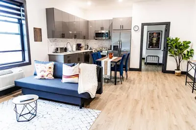a living room with a blue couch and a kitchen at Two Bedrooms with Free Parking Near NYC in West New York