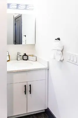 a white bathroom with a sink and a mirror at Two Bedrooms with Free Parking Near NYC in West New York
