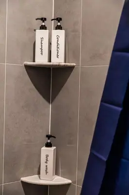 three soap bottles sitting on shelves in a bathroom at Two Bedrooms with Free Parking Near NYC in West New York