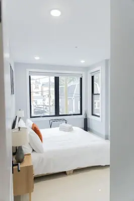a white bedroom with a large bed and a window at Easy Access to Times Square and Metlife Stadium Free Parking in West New York