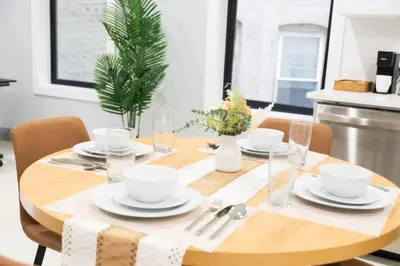 a wooden table with plates and glasses on it at Easy Access to Times Square and Metlife Stadium Free Parking in West New York