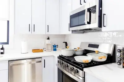 a kitchen with white cabinets and a stove top oven at Modern 1 Bedroom Apt with Quick NYC Access and Free Parking in West New York