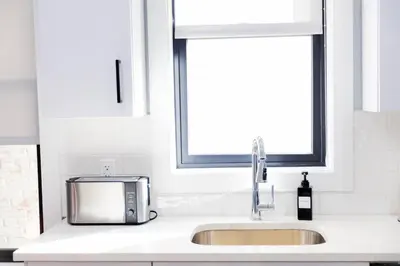 a kitchen sink with a microwave and a window at Modern 1 Bedroom Apt with Quick NYC Access and Free Parking in West New York