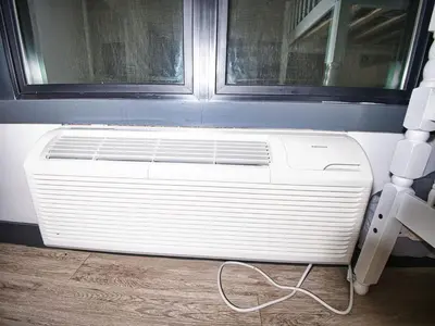 a white air conditioner sitting on the floor next to a window at Explore New York City-20 Minutes Away With Parking in West New York