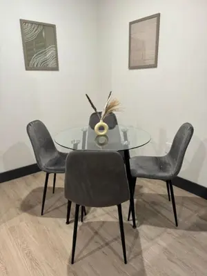 a glass table with four chairs and a vase on it at Free Indoor Parking 25 Minutes to NYC in West New York