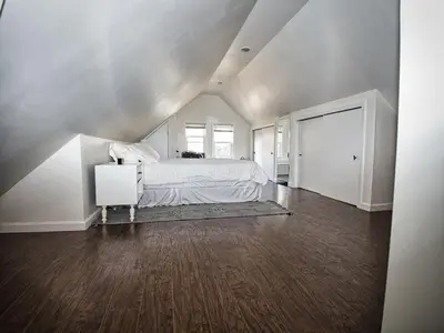 a white bedroom with a bed and a wooden floor at Comfy 3rd Floor Studio Near NYC in Ridgefield Park