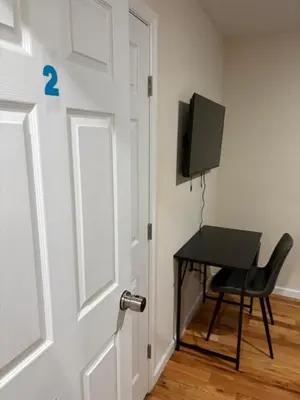 a door with a desk and a television in a room at Luxury Apartment near Airport in Newark