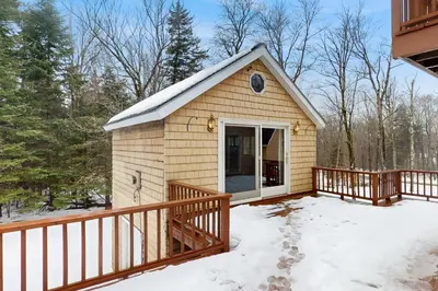 a small house with a deck in the snow at Owls' Hollow in West Dover