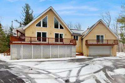 a wooden house with a garage in the snow at Owls' Hollow in West Dover