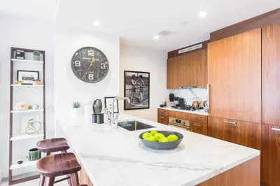 a kitchen with a large clock and a bowl of fruit on a counter at Union Residence by Rove - Gorgeous Williamsburg Condo in Brooklyn